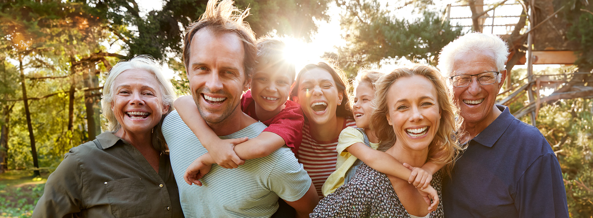 The image shows a family of five people posing together outdoors during the daytime.