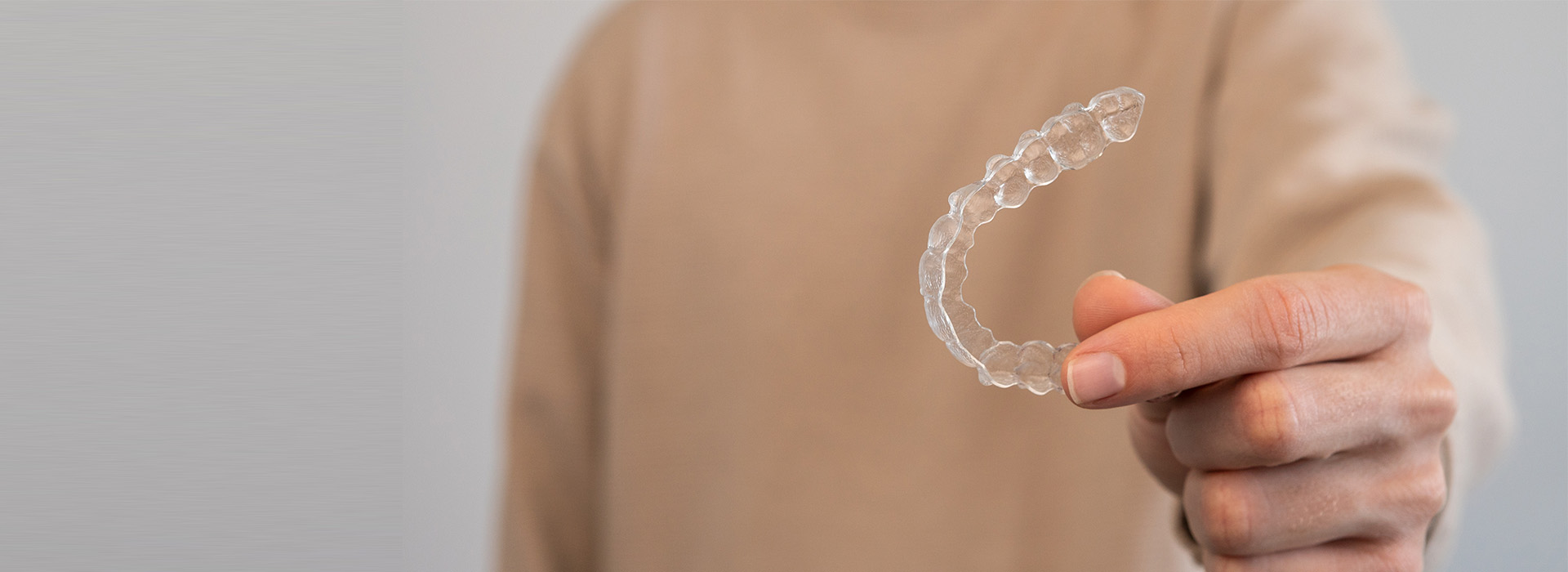 A person s hand holding a clear plastic object against a blurred background.