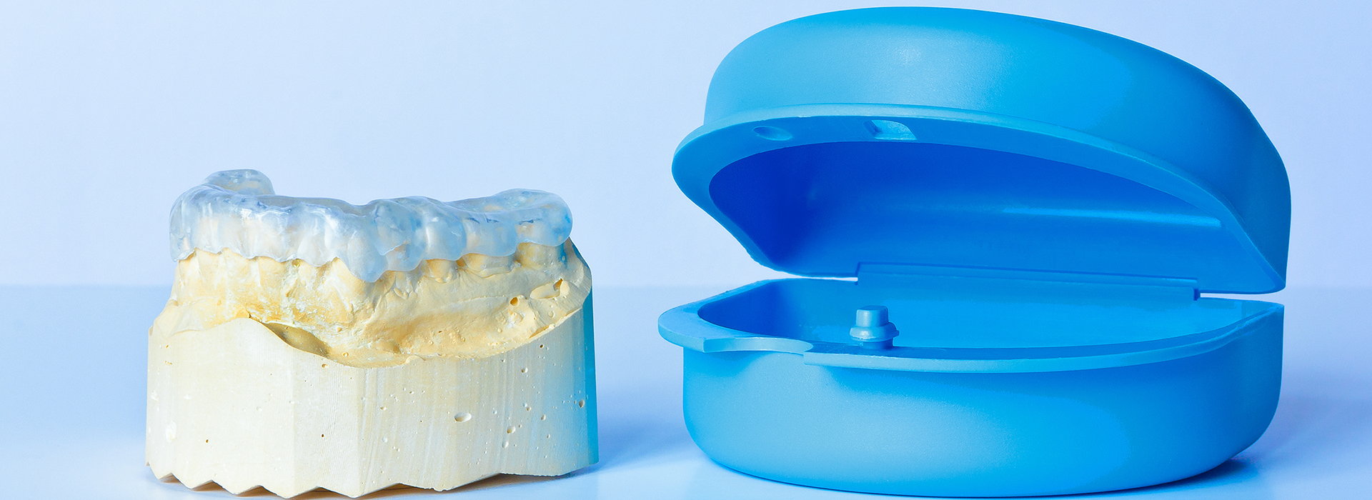 The image shows a blue dental implant next to a clear dental implant with a visible screw-like attachment, possibly indicating different types of dental implants.