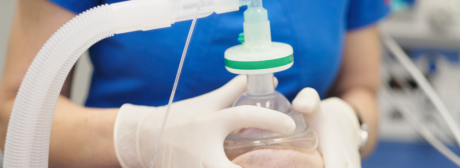 The image shows a person wearing medical gloves and working with medical equipment, specifically an IV drip bag.