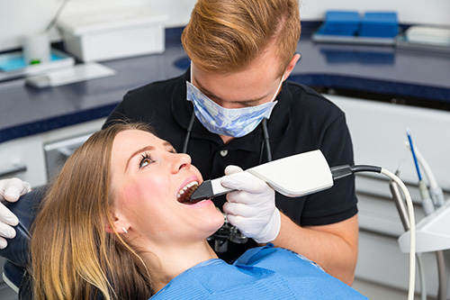 A dental hygienist is using an electric toothbrush on a patient s teeth during a dental cleaning procedure.
