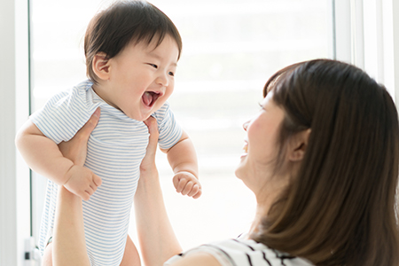 Woman holding baby with joyful expression.