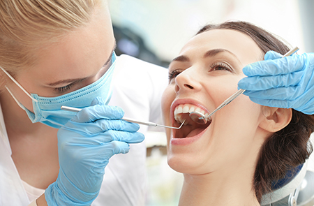 The image shows a dental professional performing a procedure on a patient s teeth, with the patient smiling and appearing relaxed under the care of the practitioner.