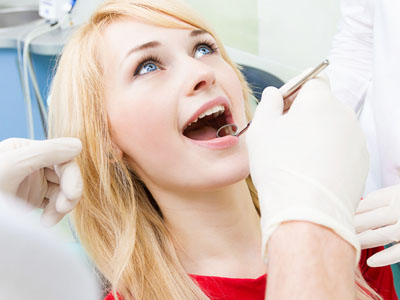 The image depicts a woman in a dental chair receiving dental treatment with a dentist standing behind her.