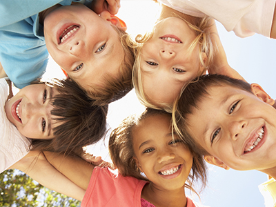 The image shows a group of children posing together with smiles on their faces, likely for a photo.
