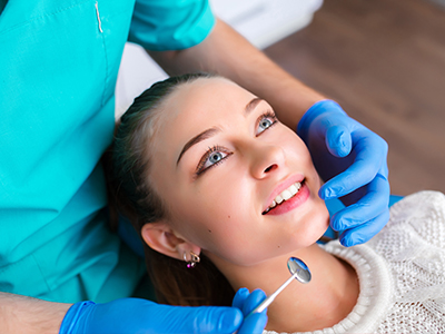 A woman receiving dental care with a dentist performing a procedure on her teeth.