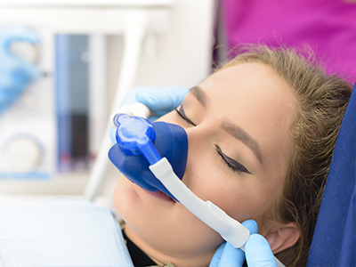 A person receiving oxygen therapy with a medical device attached to their face while lying on a hospital bed.
